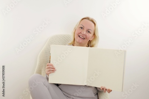 satisfied woman opened album empty space for advertising photos Memories white background white pages blond hair tracksuit