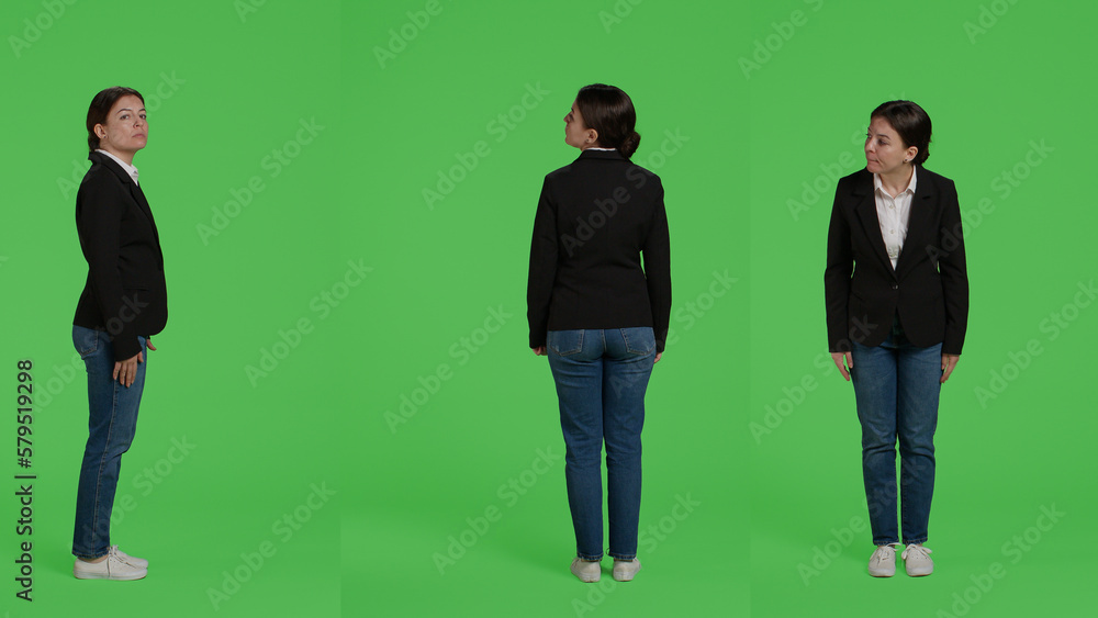 Obraz premium Female corporate model wearing formal suit standing over full body greenscreen backdrop, being casual and relaxed in studio. Company employee waiting on green screen background.