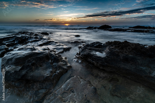 Sunset over black rocks in wavy sea Palmachim Israel