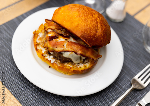 Tasty hamburger with cutlet, cheese and bacon closeup