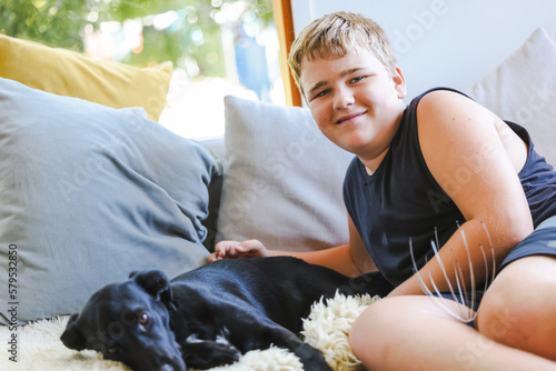 Papier peint Teen boy snuggling on couch with pet dog