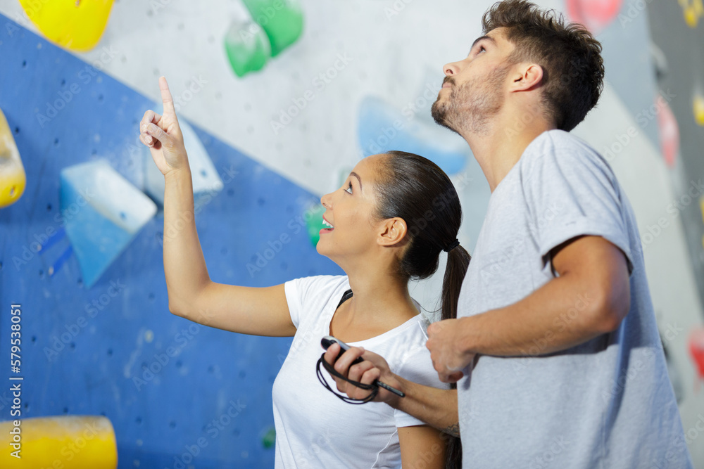 sporty male and female climbing on a climbing wall - obrazy, fototapety, plakaty 