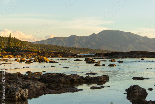Sunset and golden hour at Sharks Cove or Pupukea Beach Park, on the North Shore of Oahu, Hawaii. Calm waters and rocky beach.