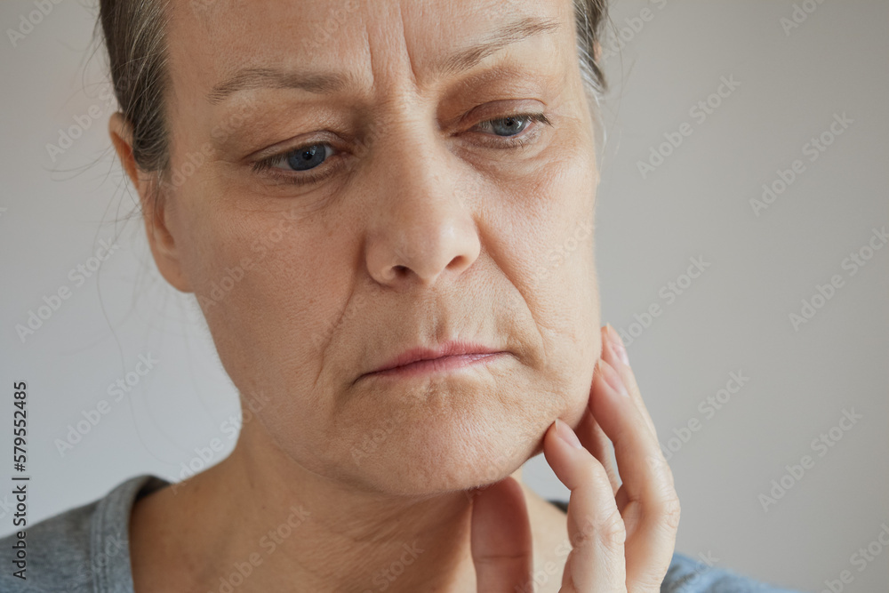 Close-up senior woman suffering from toothache, touching her cheek with her hand - obrazy, fototapety, plakaty 