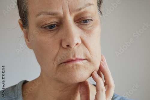 Close-up senior woman suffering from toothache, touching her cheek with her hand