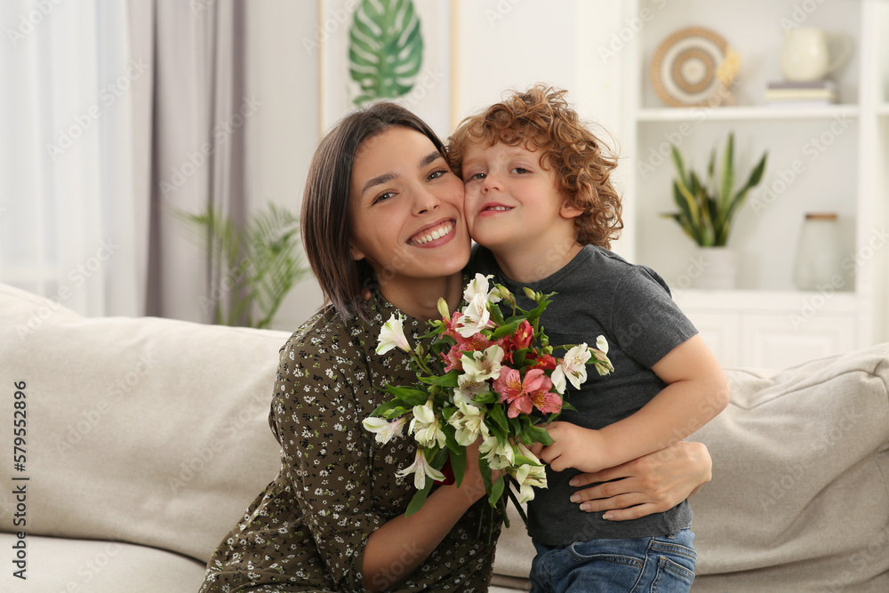 Happy woman with her cute son and bouquet of beautiful flowers at home. Mother's day celebration Happy woman with her cute son and bouquet of beautiful flowers at home. Mother's day celebration