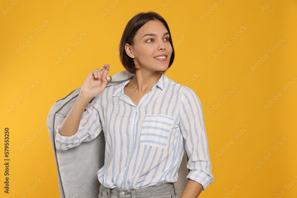 Woman holding garment cover with clothes on yellow background. Dry-cleaning service Woman holding garment cover with clothes on yellow background. Dry-cleaning service
