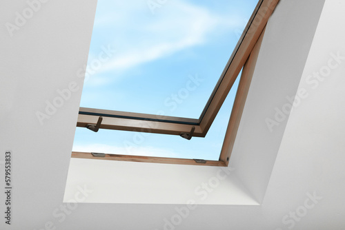 Bilde på lerret Open skylight roof window on slanted ceiling in attic room, low angle view