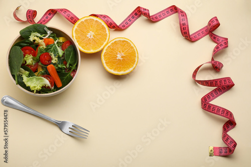 Measuring tape, salad, halves of orange and fork on yellow background, above view. Space for text