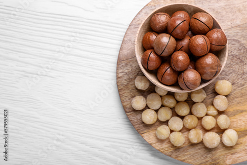 Delicious Macadamia nuts on white wooden table, top view. Space for text