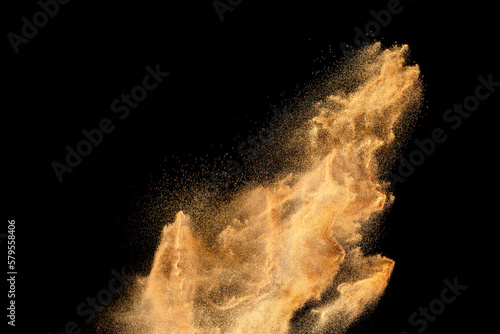 Brown sand explosion isolated on black background. Freeze motion of sandy dust splash.