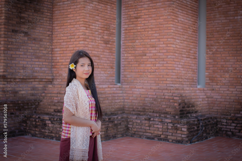Close up beautiful thai woman in traditional thai dress standing and looking to to the camera in an old temple with a smile. Close up beautiful thai woman in traditional thai dress standing and looking to to the camera in an old temple with a smile.