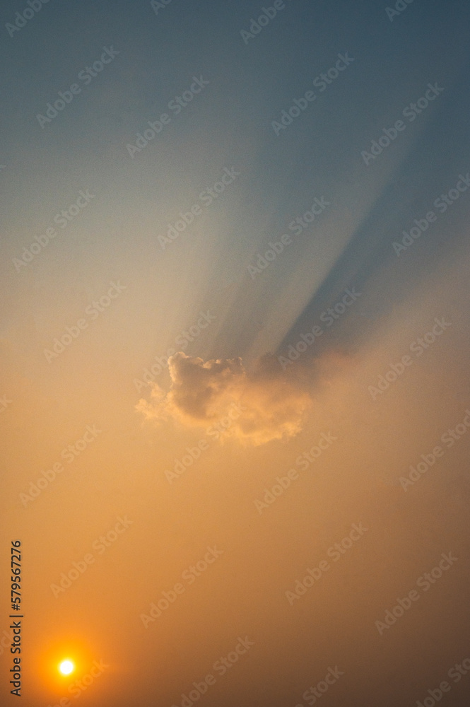 A cloud in the sky with the sun setting behind it