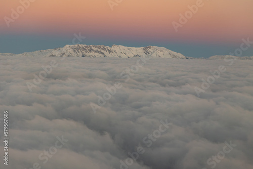 Peaks of snowy mountains over gray clouds in the dawn sky