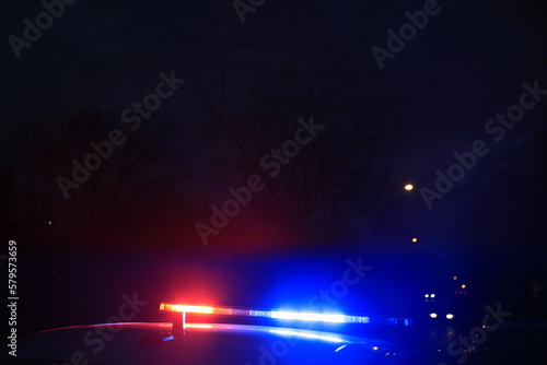 Police car emergency lights are illuminated at dusk while cops search for suspect 