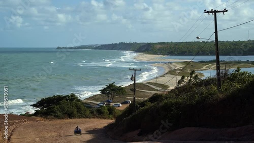 Gramame beach where the ocean meets the large river with waves crashing into the sand and a four wheeler driving down the dirt road, near the beach capital city of Joao Pessoa in Paraiba, Brazil photo