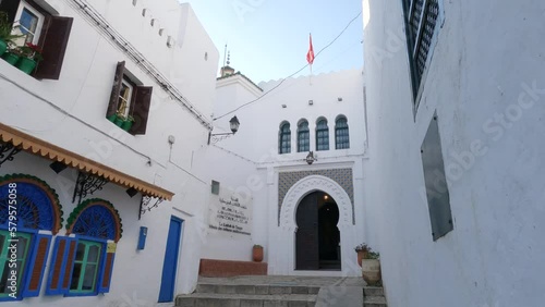Flag of Morocco flutters over ancient Kasbah fortifications in the heart of bustling Tangier medina