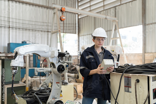Female engineer control robot arm by remote robot control in workshop. Woman technician working with control automatic robot arm system welding. Industry robot manufacturing technology