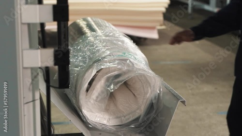 Close-up of compressed mattress wrapped in stretch film on a factory automated packaging line for compressed mattresses photo
