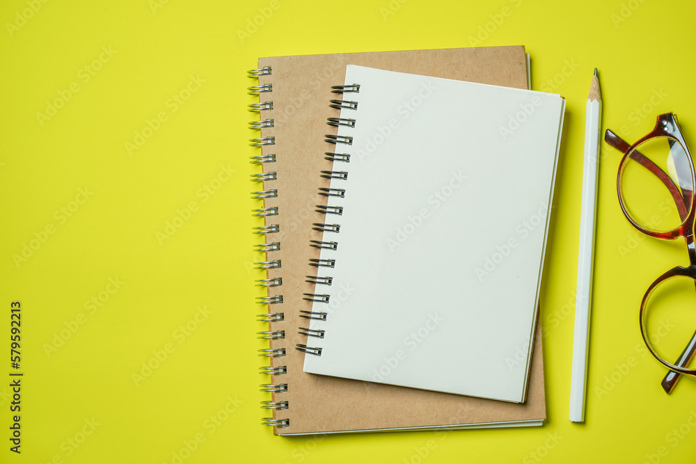Top view Notebook with blank page on yellow background Top view Notebook with blank page on yellow background