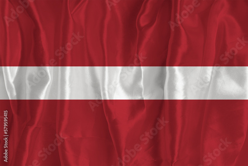 The flag of Latvia on a silk background is a great national symbol. Texture of fabrics The official state symbol of the country