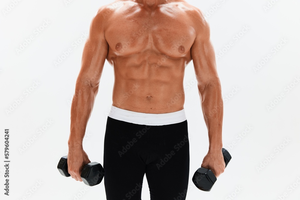 Fototapeta premium Man athletic body bodybuilder posing with dumbbells with naked torso abs full-length in the background, fitness class. Advertising, sports, active lifestyle, competition, challenge concept. 