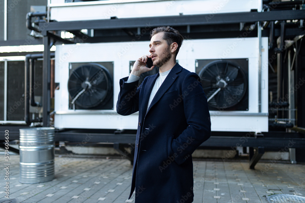 portrait of a confident european businessman talking on the phone against the backdrop of an office building