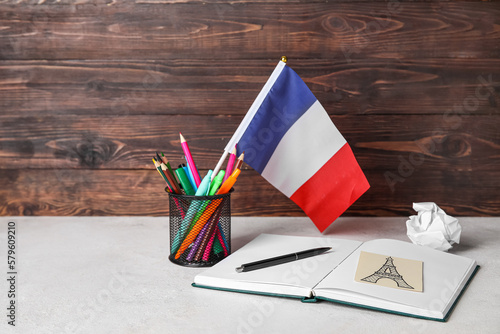Flag of France with stationery on table near dark wooden wall