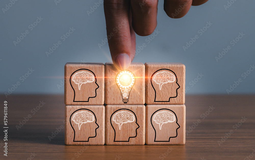 brainstorming creative idea and innovation. Hand putting over wooden cube block with light bulb icon on many people together having an idea symbolized by icons on cubes.