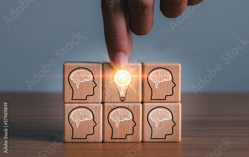 brainstorming creative idea and innovation. Hand putting over wooden cube block with light bulb icon on many people together having an idea symbolized by icons on cubes.