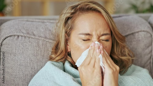 Sick asian woman blowing nose in home for allergy, covid virus and sinusitis cold. Sneeze, flu and allergies of female face on couch in recovery from healthcare problem, medical disease and hayfever photo