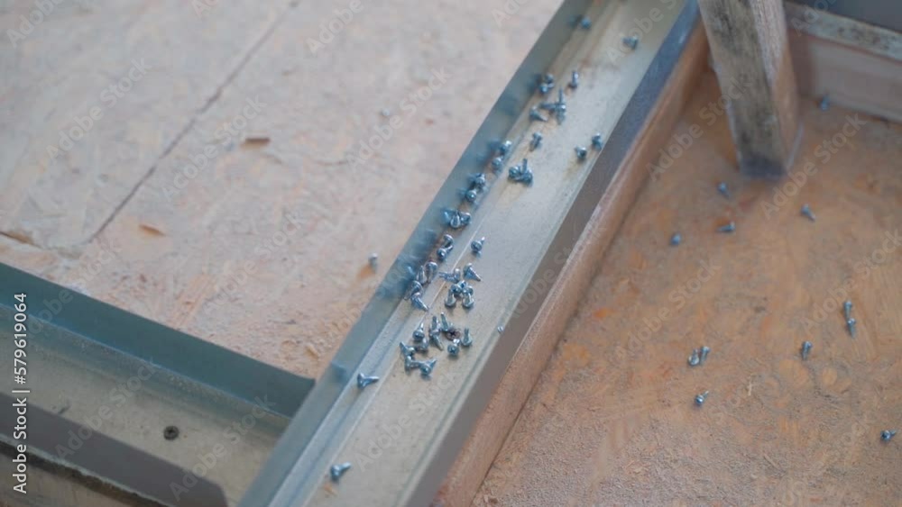 Self-tapping bugs for the metal profile were scattered on the floor, Assembly of the frame from the U profile for the wall of drywall. Smooth camera movement Self-tapping bugs for the metal profile were scattered on the floor, Assembly of the frame from the U profile for the wall of drywall. Smooth camera movement