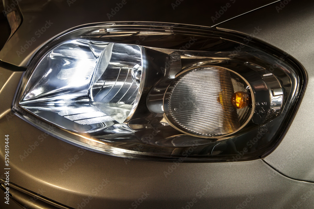 Headlight on. The headlight of a passenger car. The headlight of the car. Headlight close-up. Headlight on. The headlight of a passenger car. The headlight of the car. Headlight close-up.