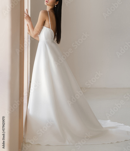 Leinwand Poster Side view of beautiful brunet bride in long white wedding dress with the naked back