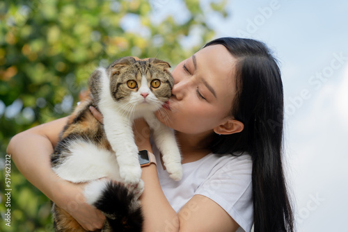 Beautiful young girl holds a Scottish cat with orange eyes  outdoor  close-up