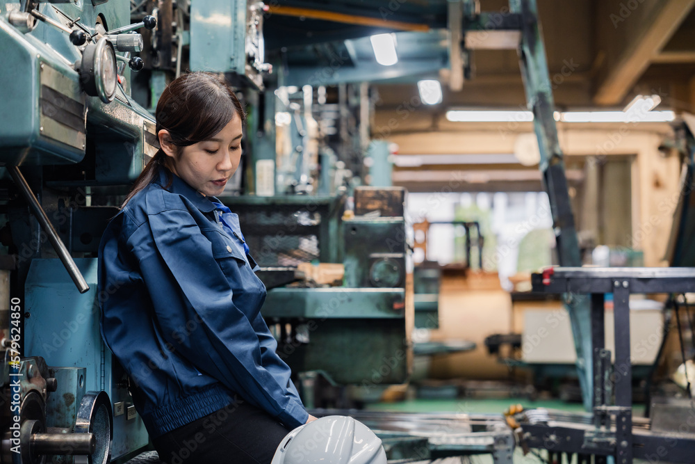 過労でやる気をなくす工場労働者の女性 過労でやる気をなくす工場労働者の女性