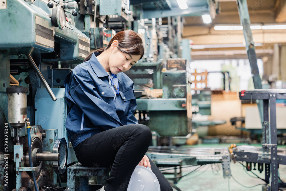 過労でやる気をなくす工場労働者の女性 過労でやる気をなくす工場労働者の女性