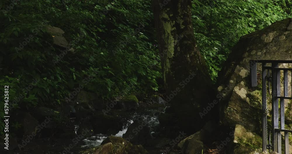 Fast cascading forest stream flowing along stones and iron railing. Fast cascading forest stream flowing along stones and iron railing.
