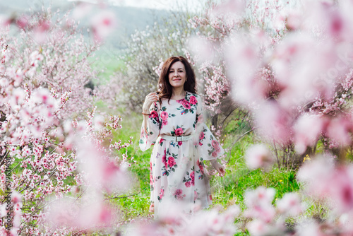 a woman stands in a garden of flowering pink trees nature park spring