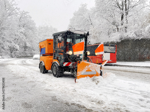 Snow plough in winter clears road, pavement and bike path