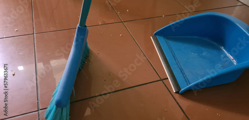 Sweeper and blue dustpan on tiled floor