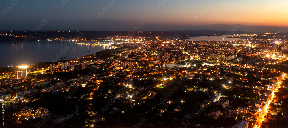 A panoramic aerial view of the city near sea at night.