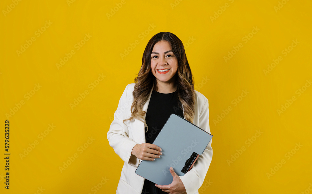 Fototapeta premium young hispanic business woman holding folders posing isolated over yellow background in Mexico Latin America