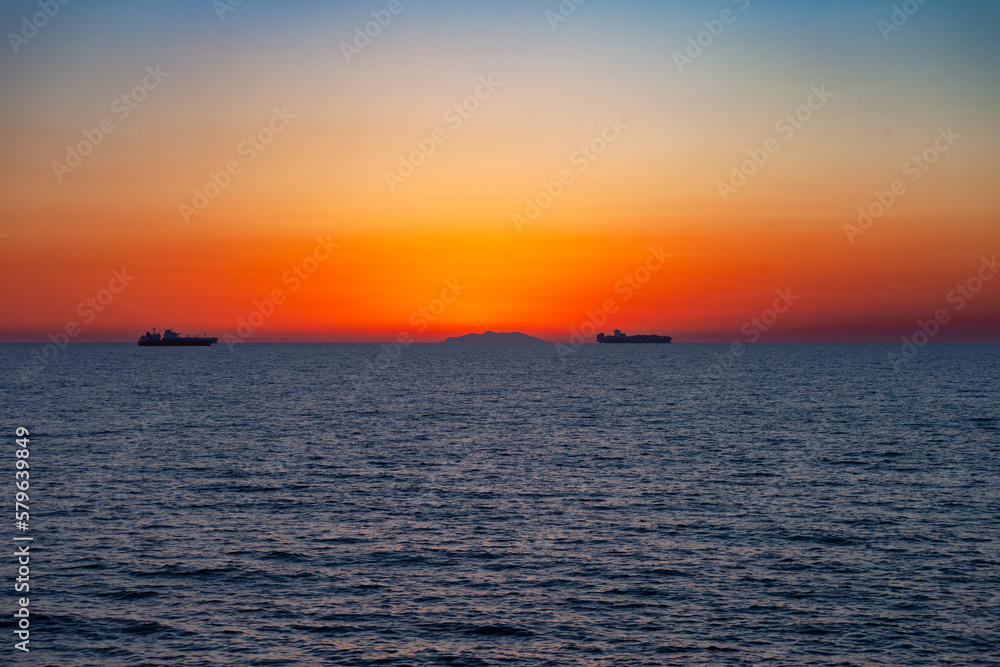 tramonto scuro serale costa mediterranea con due navi all'orizzonte