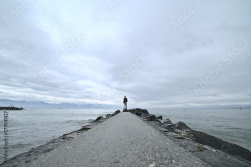 Personne au bout d'un ponton du lac Léman en Suisse à Lausanne sur des rochers impressionnant nuageux