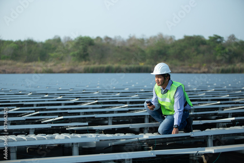 An young engineer is checking with tablet an operation of sun and cleanliness on field of photovoltaic solar panels on a sunset. Concept:renewable energy, technology,electricity,service, green,future