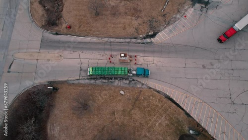 Flatbed Semi truck driver enters truck stop while red tractor with white trailer exits. In the middle security guard check. Aerial 4k USA photo