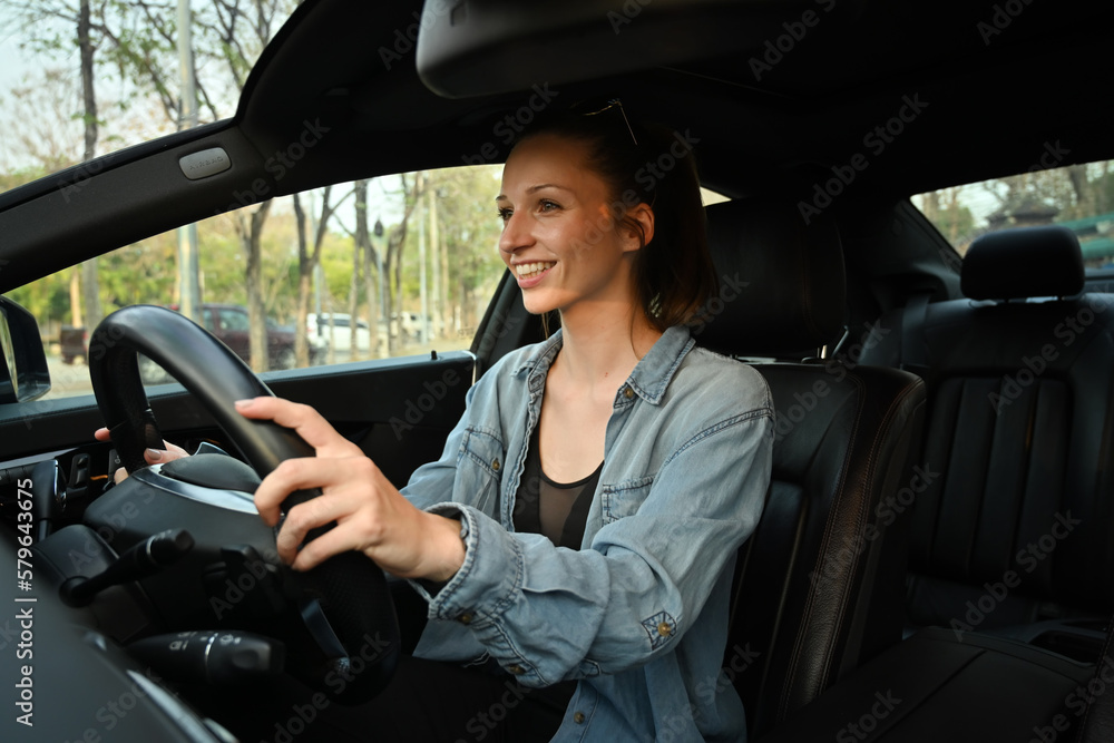 Naklejka premium Young sportswoman driving a car during going to her training in fitness centre or gym. Healthy lifestyle, fitness lifestyle concept