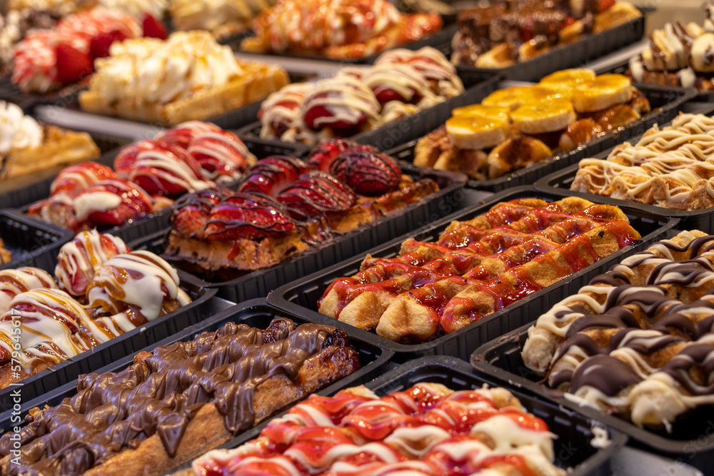Traditional Belgian waffles decorated with fruit and cream lie in a row on the table close-up