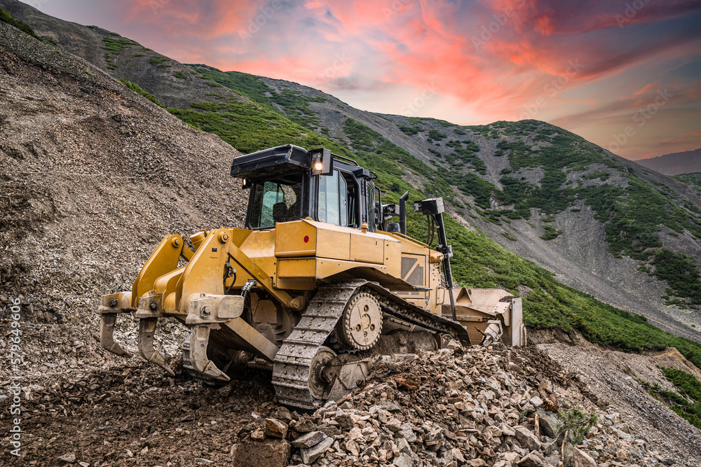 Yellow excavator on new construction site, with the bright sun and nice red sky in the background Yellow excavator on new construction site, with the bright sun and nice red sky in the background